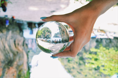 Close-up of hand holding crystal ball with reflection