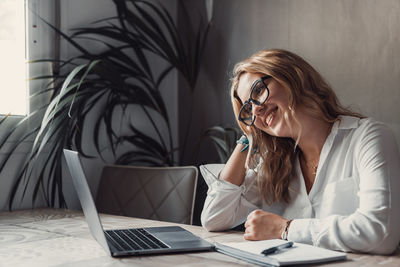 Businesswoman using laptop while sitting on table at home