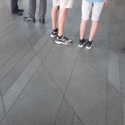 Low section of people standing on tiled floor