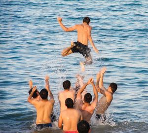 Rear view of shirtless men enjoying in lake