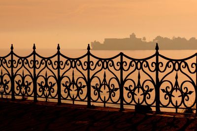 Metal gate of building against sky during sunset