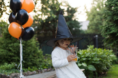 Girl wearing witch hat drinking juice