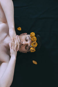 Directly above shot of shirtless man wearing flowers while lying down