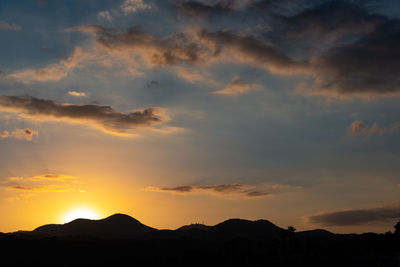 Silhouette mountains against dramatic sky during sunset