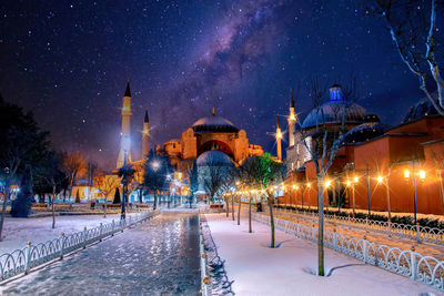 Illuminated buildings against sky during winter at night