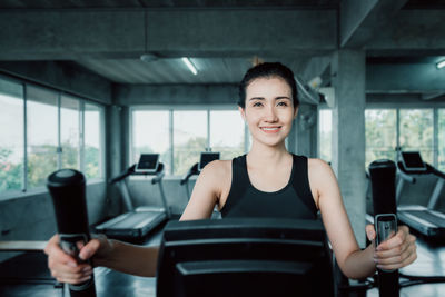 Portrait of smiling young woman on treadmill at gym