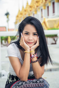 Asian woman in a white t-shirt, she is sitting put her chin on her hands while traveling in asia