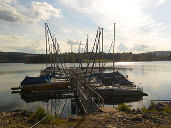 Sailboats moored in lake against sky