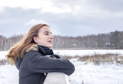Smiling girl looking away on snow covered land