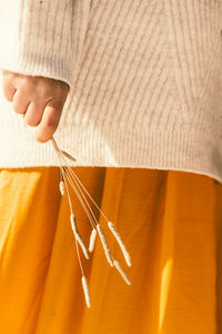 Woman in orange skirt holding dry spikelets in her hands