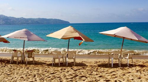 Chairs by parasols at sandy beach