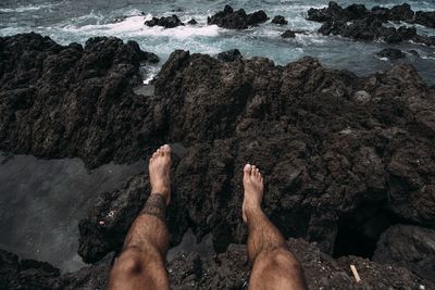 Low section of people on rock by sea