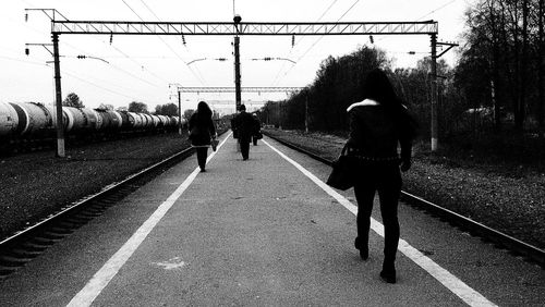 Silhouette people on railroad station against sky