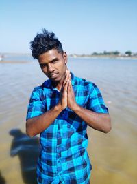 Portrait of man with hands clasped standing at beach