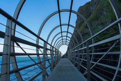 Footbridge over sea against clear sky