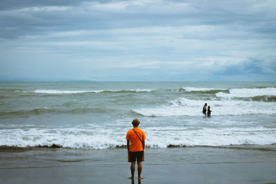 People at beach against cloudy sky