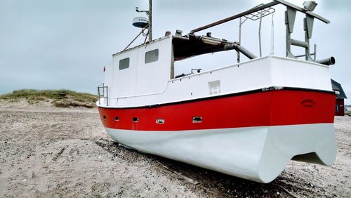 Red ship on beach against sky