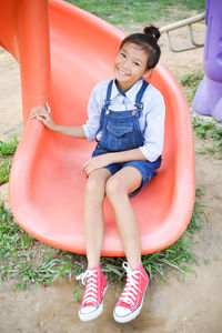 Portrait of girl sitting on slide at park