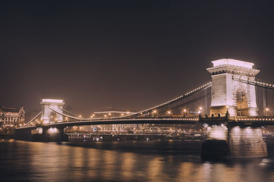 Illuminated bridge over river at night