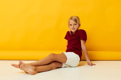 Full length of young woman exercising against yellow background