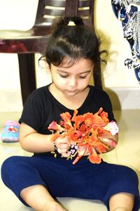 Close-up of girl sitting with pink flower