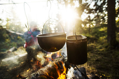 Food being cooked in utensils over bonfire on sunny day