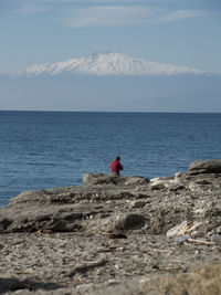 Rear view of man by rock formations and sea against sky