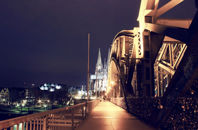 Illuminated hohenzollern bridge against cologne cathedral at night