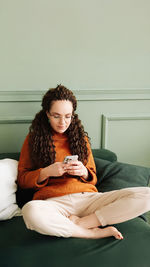 Young woman sitting on sofa at home