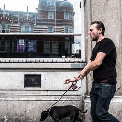 Man with dog standing in front of building
