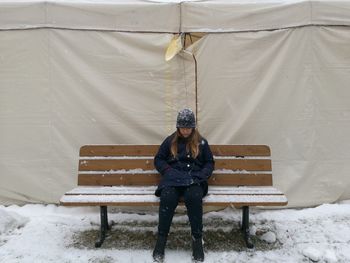 Full length of woman sitting on snow