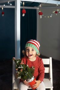 Cheerful girl sitting on chair during christmas