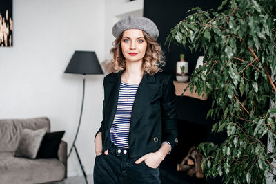 Portrait of young woman standing against wall