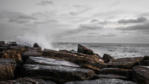 Scenic view of rocks in sea against sky