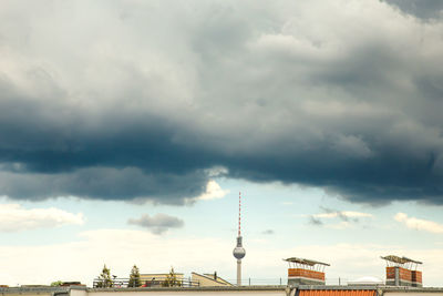 Low angle view of communications tower against cloudy sky