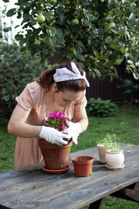 Rear view of girl looking at potted plant on table