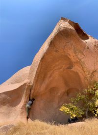 Rear view of man on rock against sky