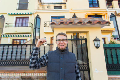 Portrait of young man standing against building