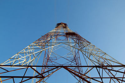 Low angle view of electricity pylon against blue sky