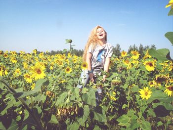 Portrait of smiling young woman standing on field against sky