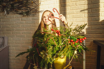 Woman with christmas tree against wall
