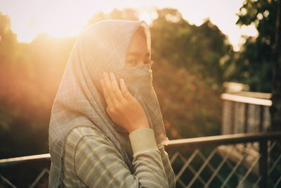 Close-up of young woman covering face with scarf