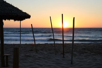 Tranquil beach with rustic parasol at sunset