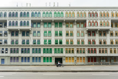 People on road by building in city