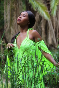 Young woman looking away while standing in forest