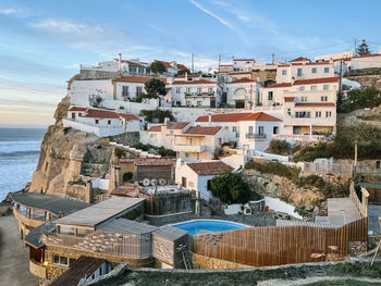 Buildings by sea against sky