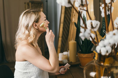 A beautiful woman in front of a mirror makes a face massage.