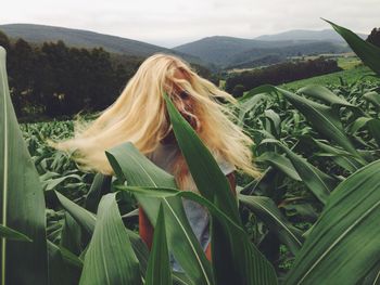 Woman tossing hair while standing amidst plants