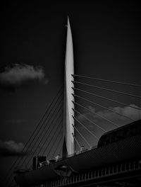 Low angle view of suspension bridge against cloudy sky