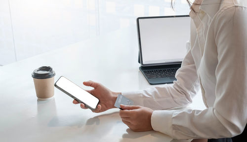 Man using mobile phone while sitting on table